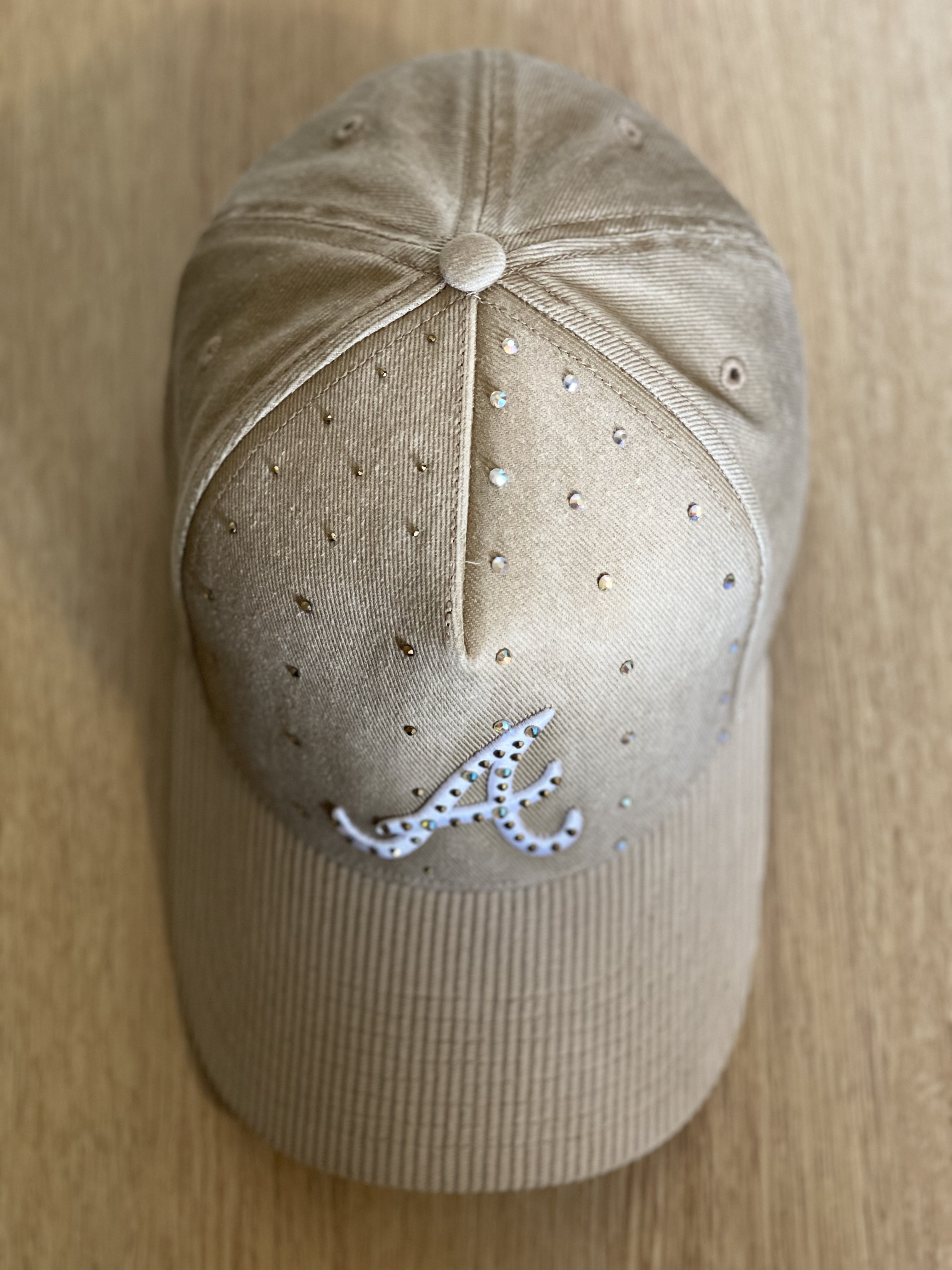 Beige Atlanta cap with crystal-studded script A and tonal scattered studs, top view.